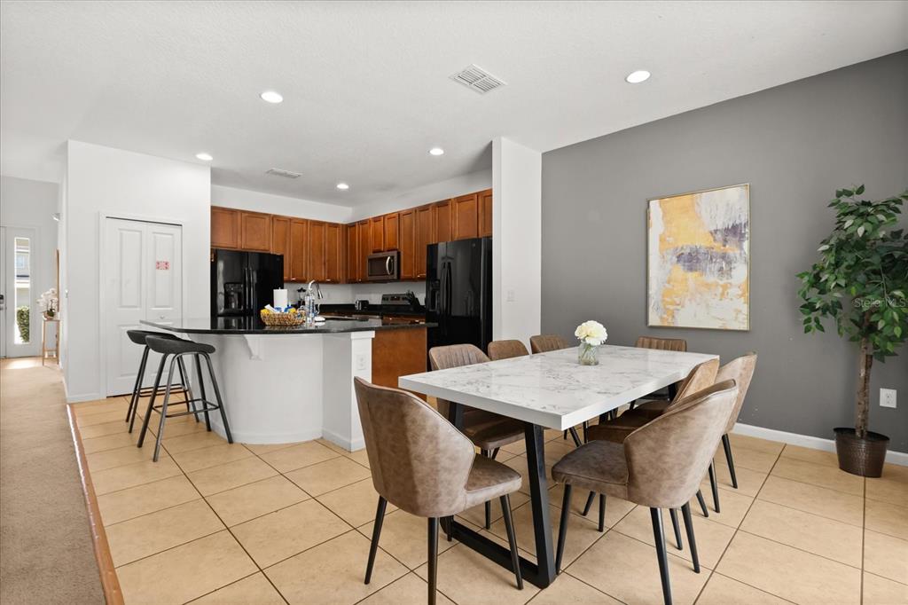 4565 Cabello Loop Kissimmee, FL 34746 - Photo 6 of 33 a kitchen with stainless steel appliances kitchen island granite countertop a refrigerator a stove a microwave oven a dining table and chairs with wooden floor