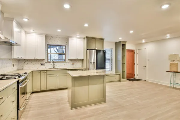 a large kitchen with stainless steel appliances granite countertop a stove a sink and a refrigerator