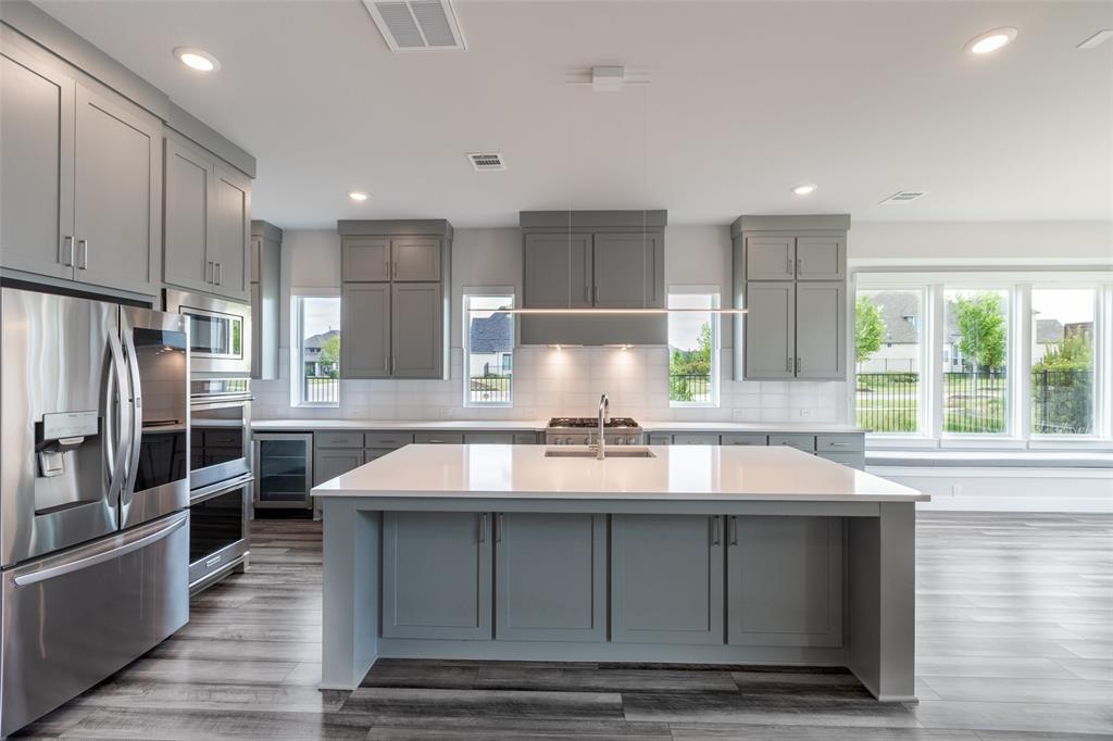 8003 Splitbeard Road Frisco, TX 75035 - Photo 12 of 40 a kitchen with kitchen island granite countertop a stove a sink and a refrigerator