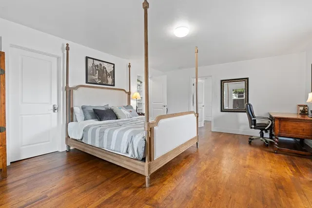 a bedroom with a bed a table and painting on the wall