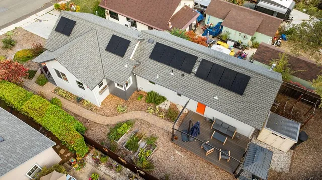 a front view of a house with a yard and covered with trees