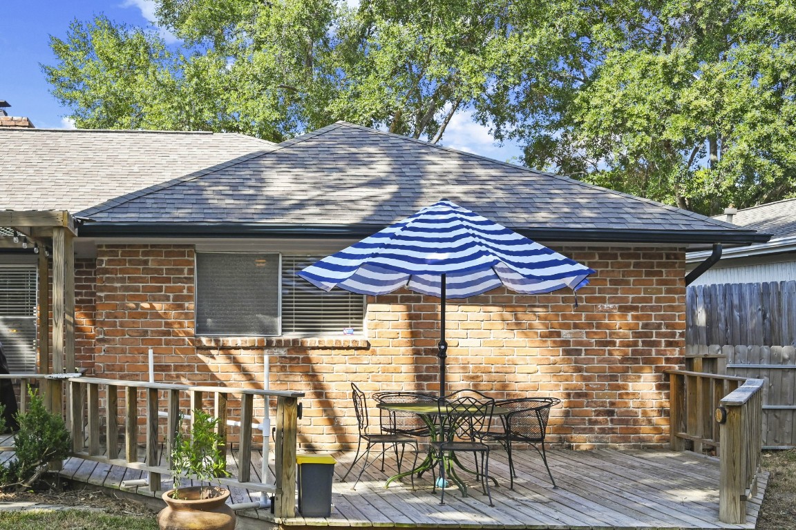 13823 Wickersham Lane Houston, TX 77077 - Photo 22 of 24 a view of a patio with table and chairs under an umbrella with wooden fence