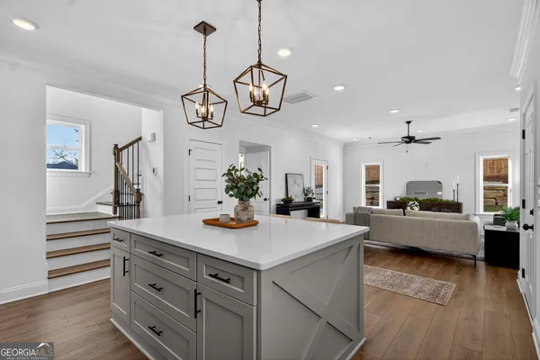 a view of living room with kitchen island stainless steel appliances furniture a chandelier and wooden floor