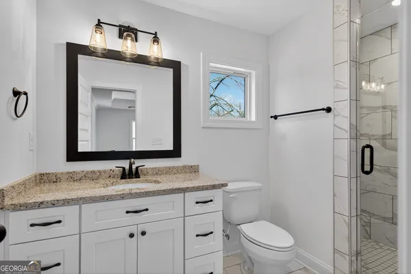 a bathroom with a granite countertop toilet sink and mirror