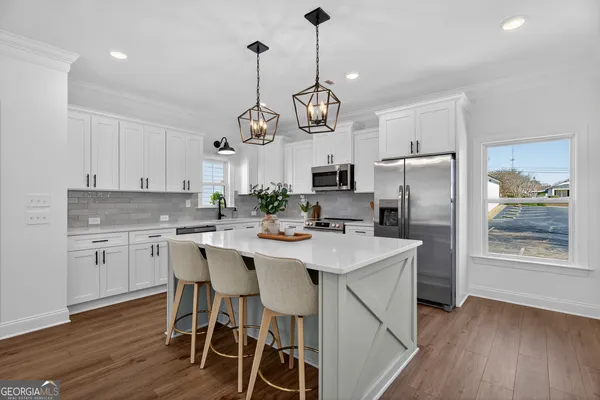 a kitchen with stainless steel appliances kitchen island granite countertop a table chairs refrigerator and microwave