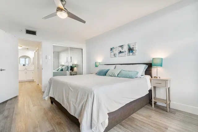 a bedroom with a bed a mirror on dresser and a chandelier