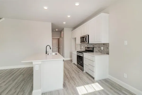 a kitchen with a sink stainless steel appliances and white cabinets