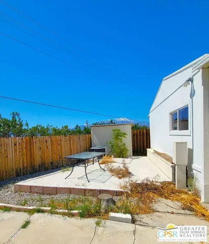 a view of a backyard with couches under an umbrella