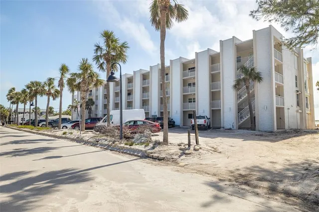 a row of palm trees sitting in a yard with a building