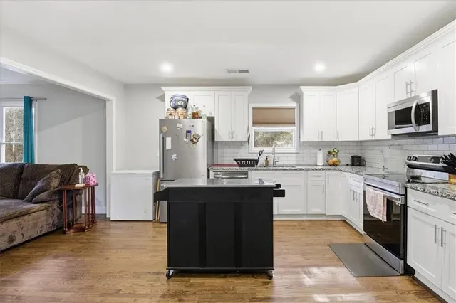 a kitchen with granite countertop a refrigerator and a stove top oven