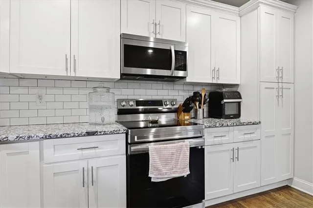 a kitchen with white cabinets and appliances