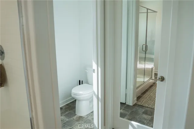 a bathroom with a granite countertop sink a toilet and a glass door