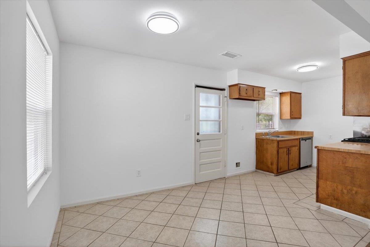 4850 Marcel Avenue Memphis, TN 38122 - Photo 12 of 20 Kitchen featuring wood finish cabinetry, light countertops, stainless steel dishwasher, and light tile patterned floors