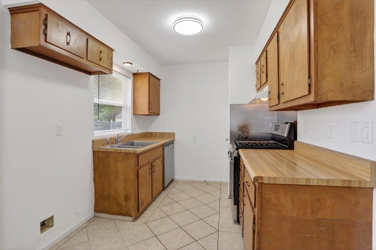 4850 Marcel Avenue Memphis, TN 38122 - Photo 10 of 20 Kitchen featuring stainless steel appliances, light countertops, wood finish cabinetry, and light tile patterned floors
