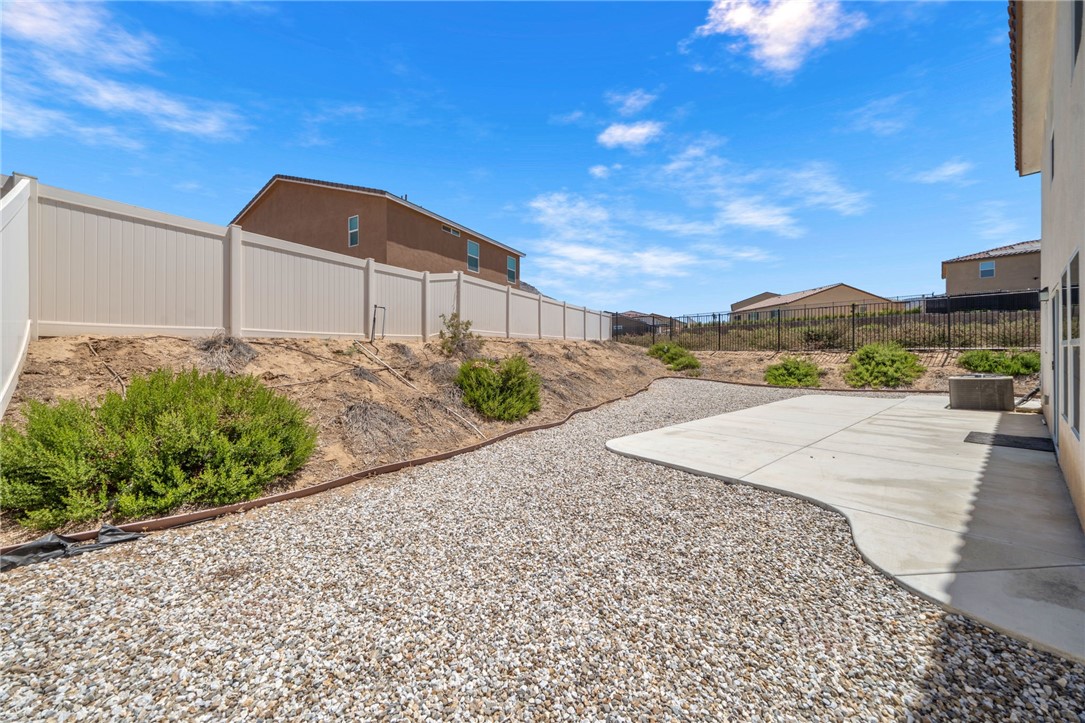 20130 Curaco Court Riverside, CA 92507 - Photo 41 of 43 Wide backyard view with concrete patio, gravel areas, and established shrubs.