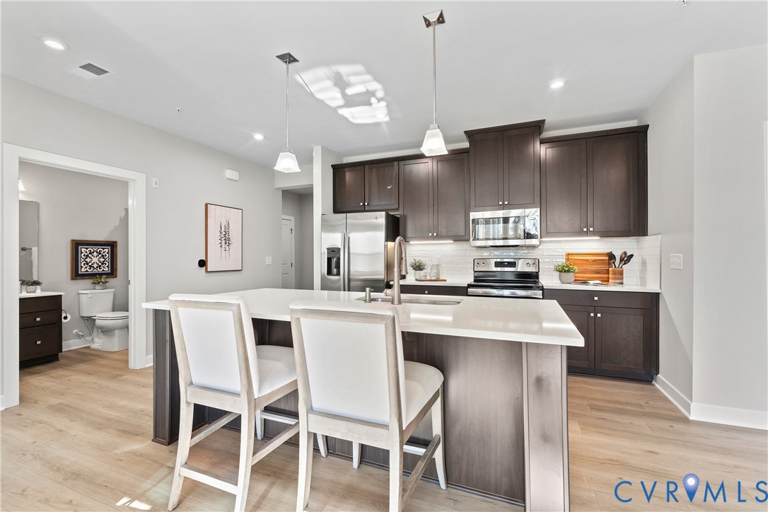 6601 Citory Way, Unit 106 Moseley, VA 23120 - Photo 8 of 39 a kitchen with stainless steel appliances kitchen island granite countertop a sink a stove a refrigerator cabinets and chairs