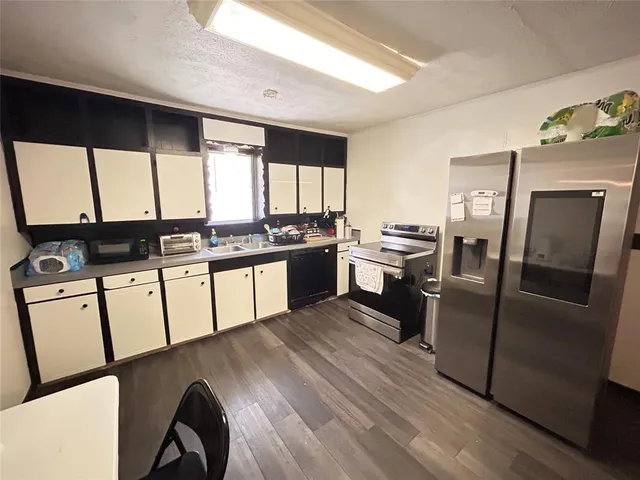 a kitchen with stainless steel appliances granite countertop a refrigerator a stove a sink dishwasher and white cabinets with wooden floor