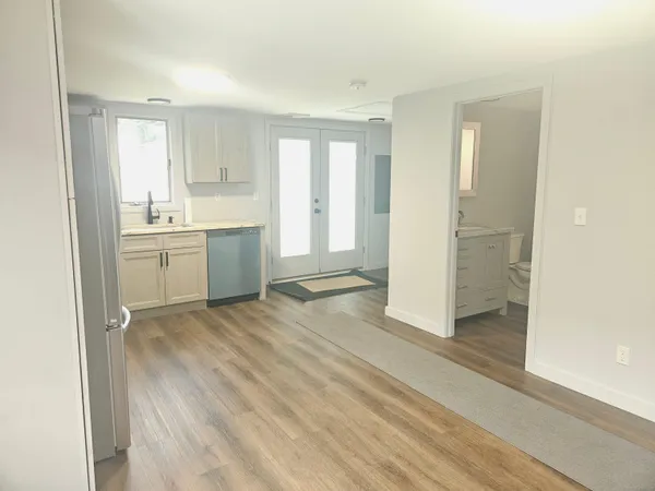 a view of a kitchen with a sink and dishwasher stove top oven with wooden floor
