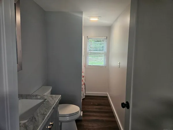a bathroom with a granite countertop toilet a sink and a mirror