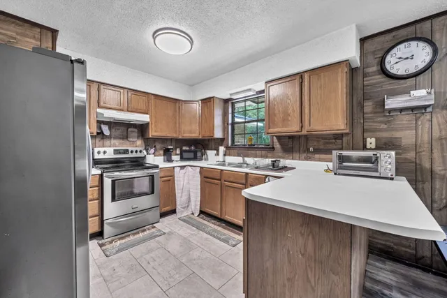 a kitchen with stainless steel appliances granite countertop a refrigerator a stove and a sink with cabinets