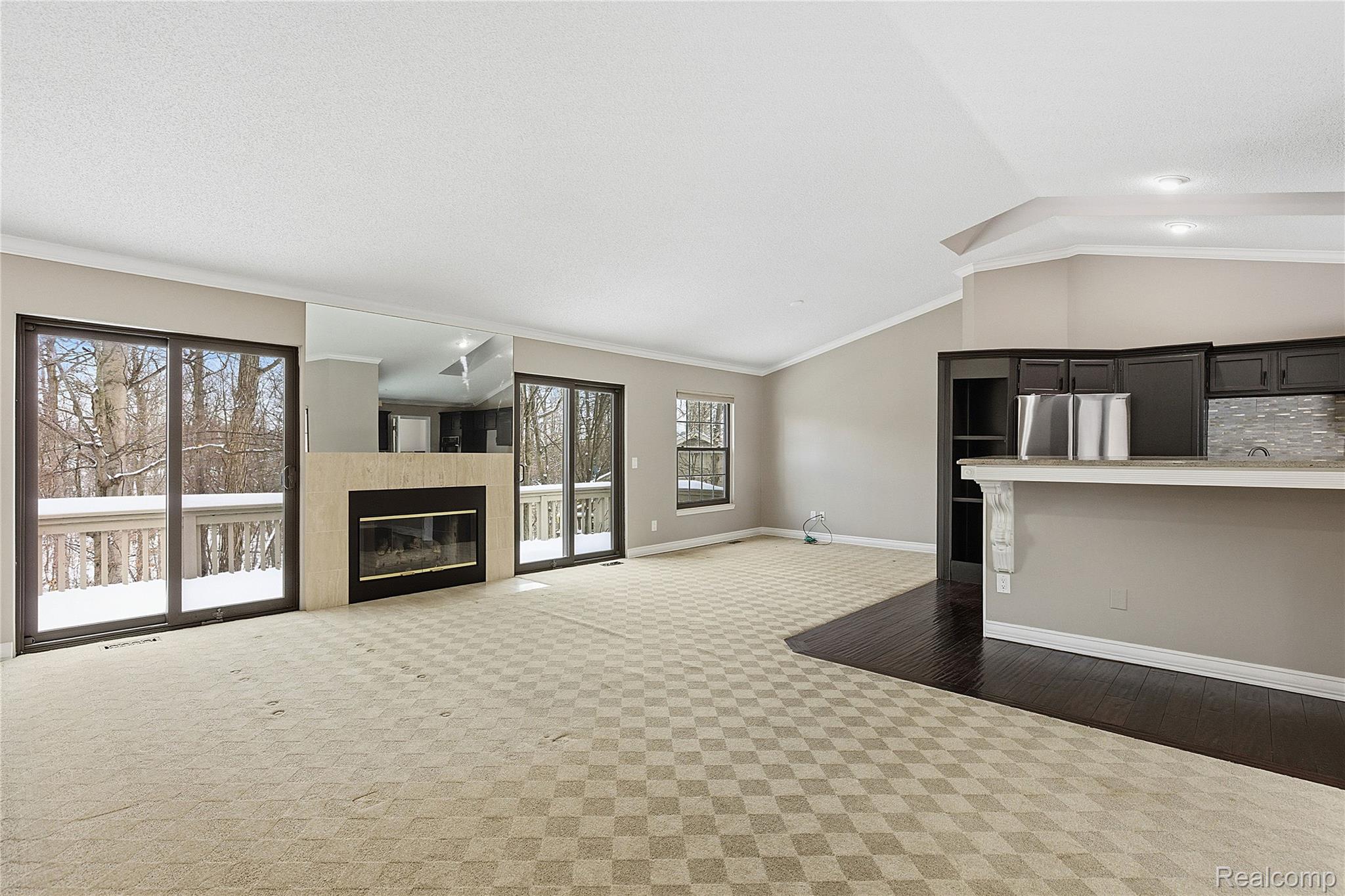 7154 Westchester Road West Bloomfield, MI 48322 - Photo 6 of 38 Unfurnished living room featuring a tiled fireplace, ornamental molding, carpet floors, and vaulted ceiling