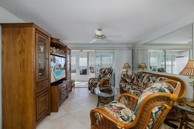 a living room with furniture a flat screen tv and floor to ceiling window