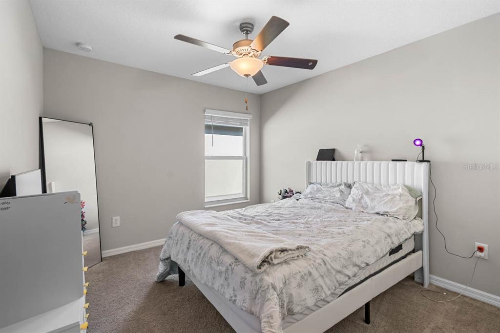 889 Calico Scallop Street Ruskin, FL 33570 - Photo 13 of 32 a bedroom with a bed and a chandelier