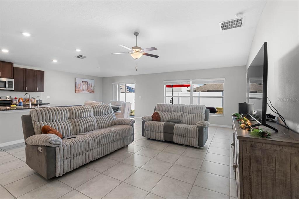 889 Calico Scallop Street Ruskin, FL 33570 - Photo 3 of 32 a living room with furniture a flat screen tv and kitchen view