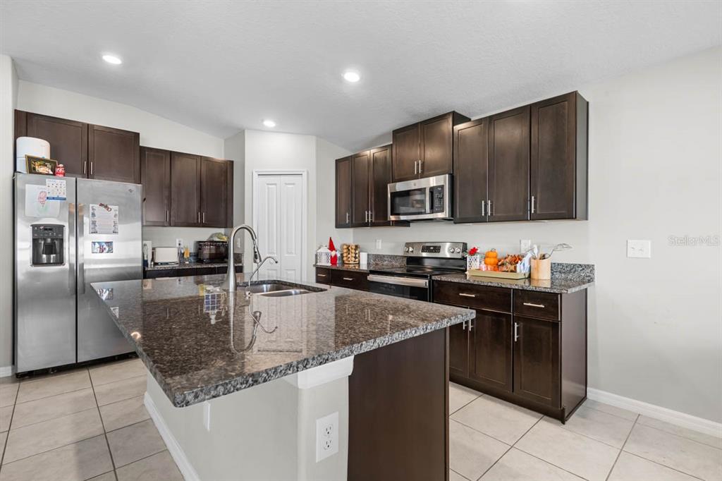 889 Calico Scallop Street Ruskin, FL 33570 - Photo 6 of 32 a kitchen with granite countertop a stove sink and cabinets
