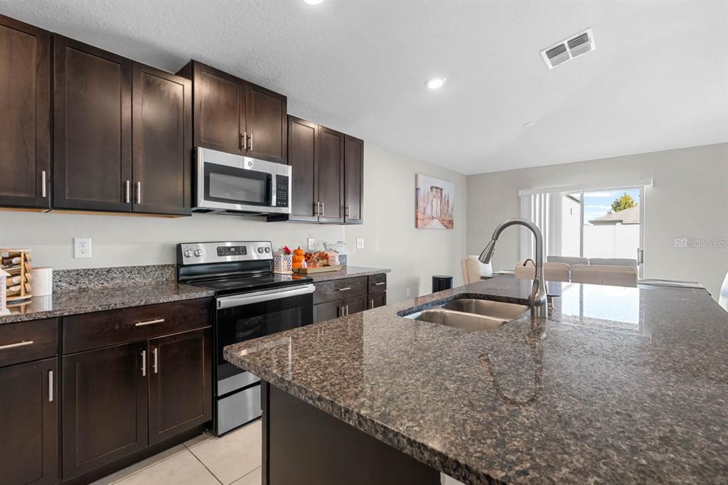 889 Calico Scallop Street Ruskin, FL 33570 - Photo 8 of 32 a kitchen with granite countertop stainless steel appliances a sink stove and cabinets