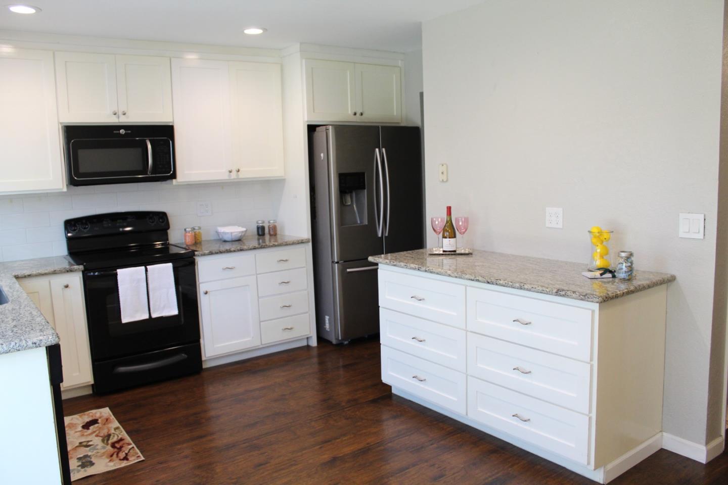 1025 Fillippelli Drive Gilroy, CA 95020 - Photo 9 of 47 a kitchen with granite countertop white cabinets and black appliances