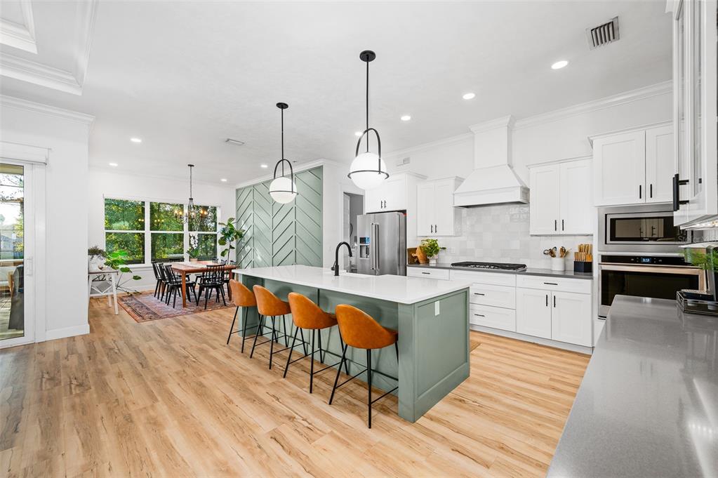 1068 Southwest 120th Drive Gainesville, FL 32607 - Photo 12 of 43 a kitchen with stainless steel appliances granite countertop a kitchen island hardwood floor sink stove dining table and chairs