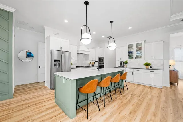 a large kitchen with stainless steel appliances kitchen island granite countertop a stove a sink dishwasher and a dining table with wooden floor