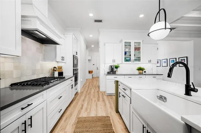 a kitchen with kitchen island stainless steel appliances a sink a stove and a wooden floors
