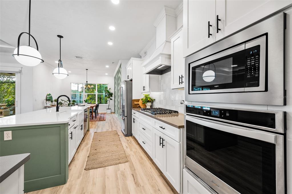 1068 Southwest 120th Drive Gainesville, FL 32607 - Photo 17 of 43 a large kitchen with stainless steel appliances granite countertop a stove a sink and a microwave