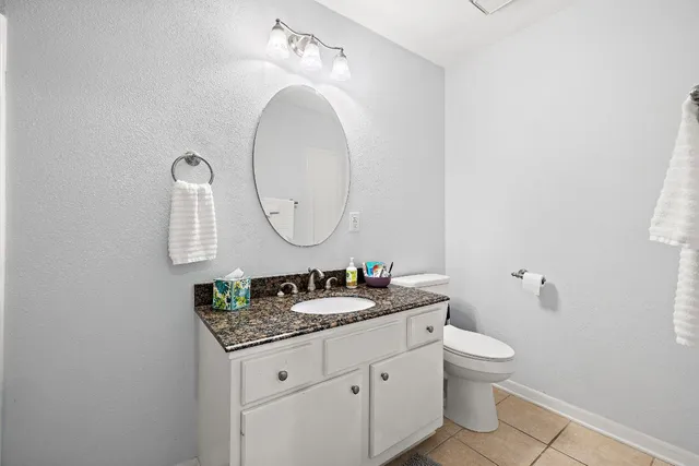 a bathroom with a granite countertop toilet a sink and a mirror