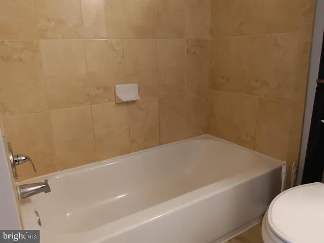 a bathroom with a white bath tub and toilet