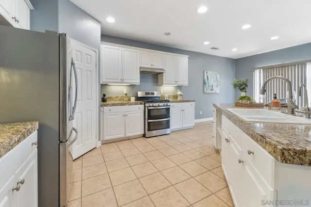 a large kitchen with stainless steel appliances granite countertop a stove a sink and a refrigerator