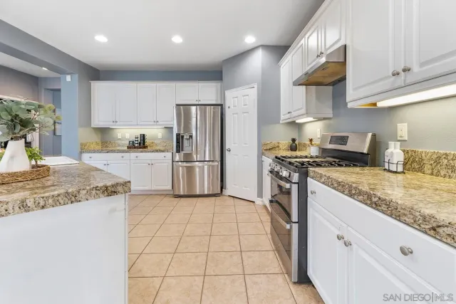 a kitchen with granite countertop a sink a counter top space stainless steel appliances and cabinets