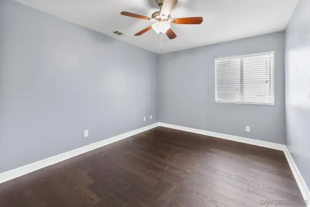 an empty room with a window and a fan