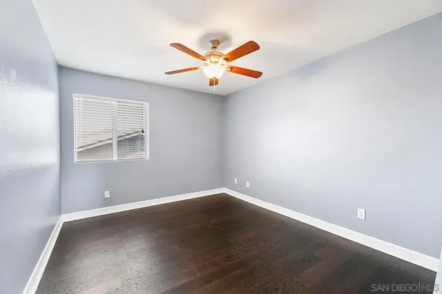 an empty room with window and ceiling fan