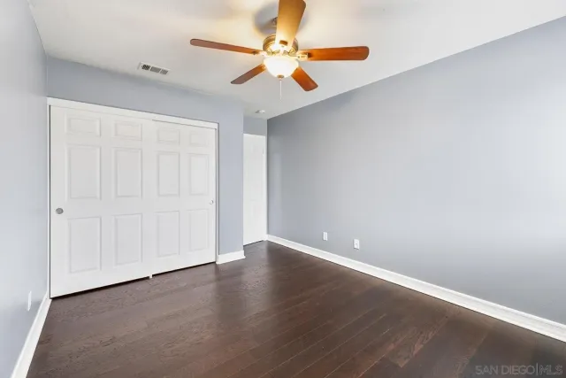 an empty room with wooden floor ceiling fan