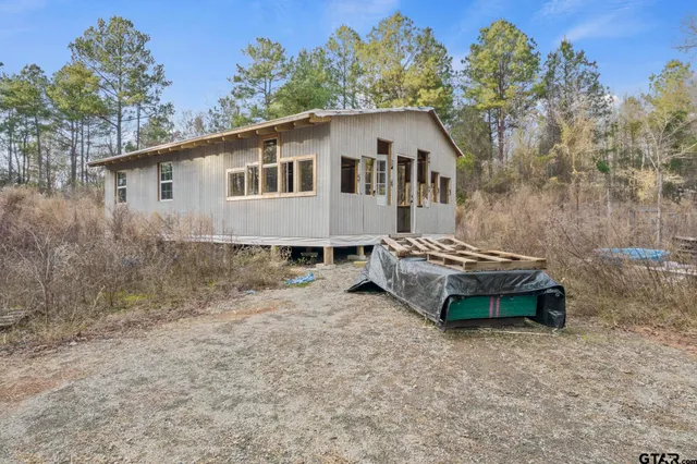 a white house that has a small yard and large trees