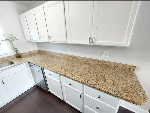 a kitchen with granite countertop white cabinets and sink