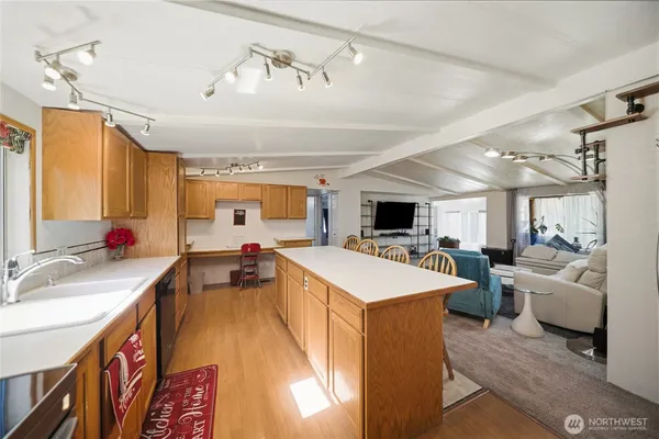 a large living room with stainless steel appliances kitchen island granite countertop a sink dishwasher a dining table and chairs with wooden floor