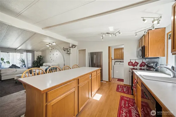 a large white kitchen with a stove a sink dishwasher and a refrigerator with wooden floor