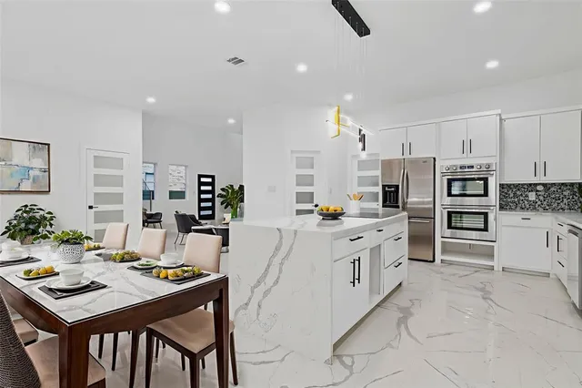 a large kitchen with kitchen island a table and chairs in it