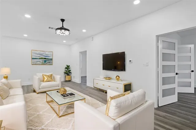 a living room with furniture a flat screen tv and kitchen view