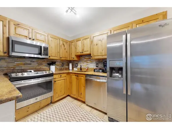 a kitchen with stainless steel appliances granite countertop a refrigerator a stove top oven a sink and dishwasher