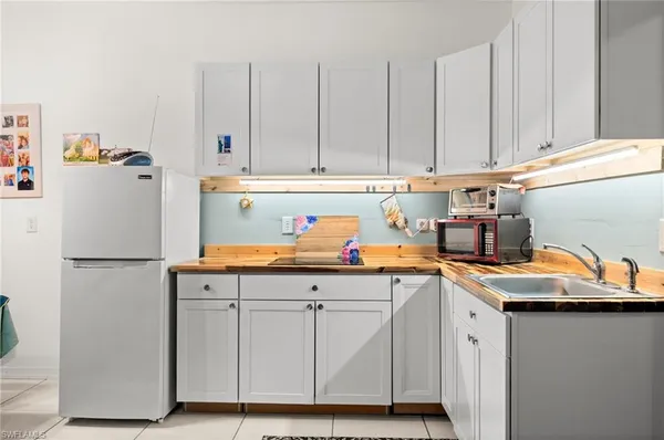 a utility room with stainless steel appliances granite countertop a sink a stove a refrigerator a washer and dryer with wooden floor